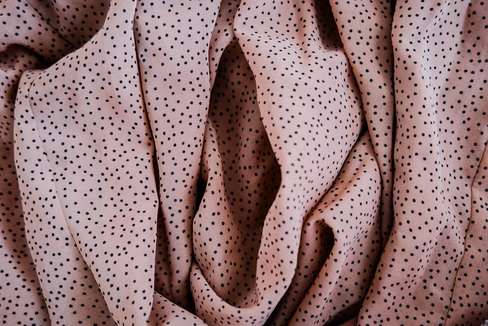 Close-up of folded pink fabric with black polka dots