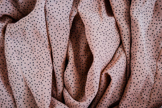 Close-up of folded pink fabric with black polka dots