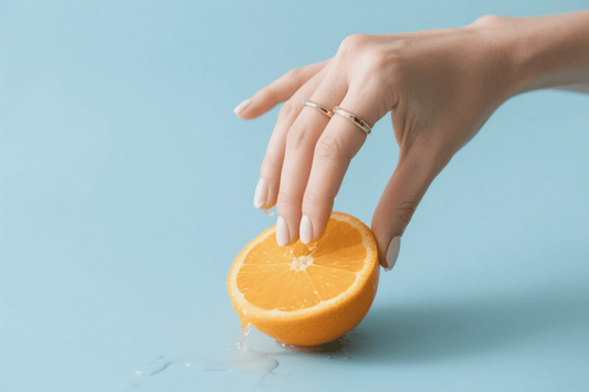 Hand squeezing half an orange over a blue surface